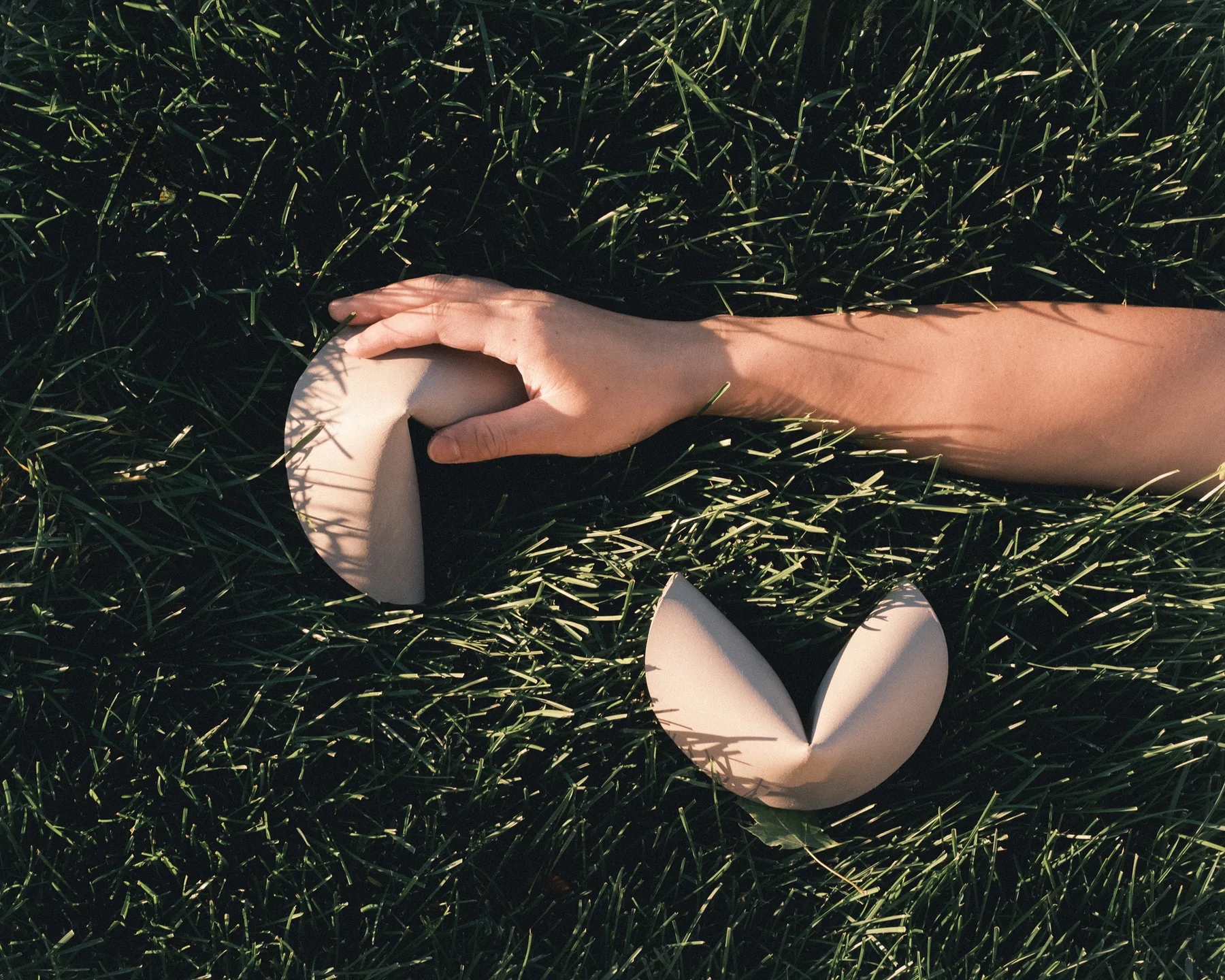 A ceramic fortune cookie object split open on grass.