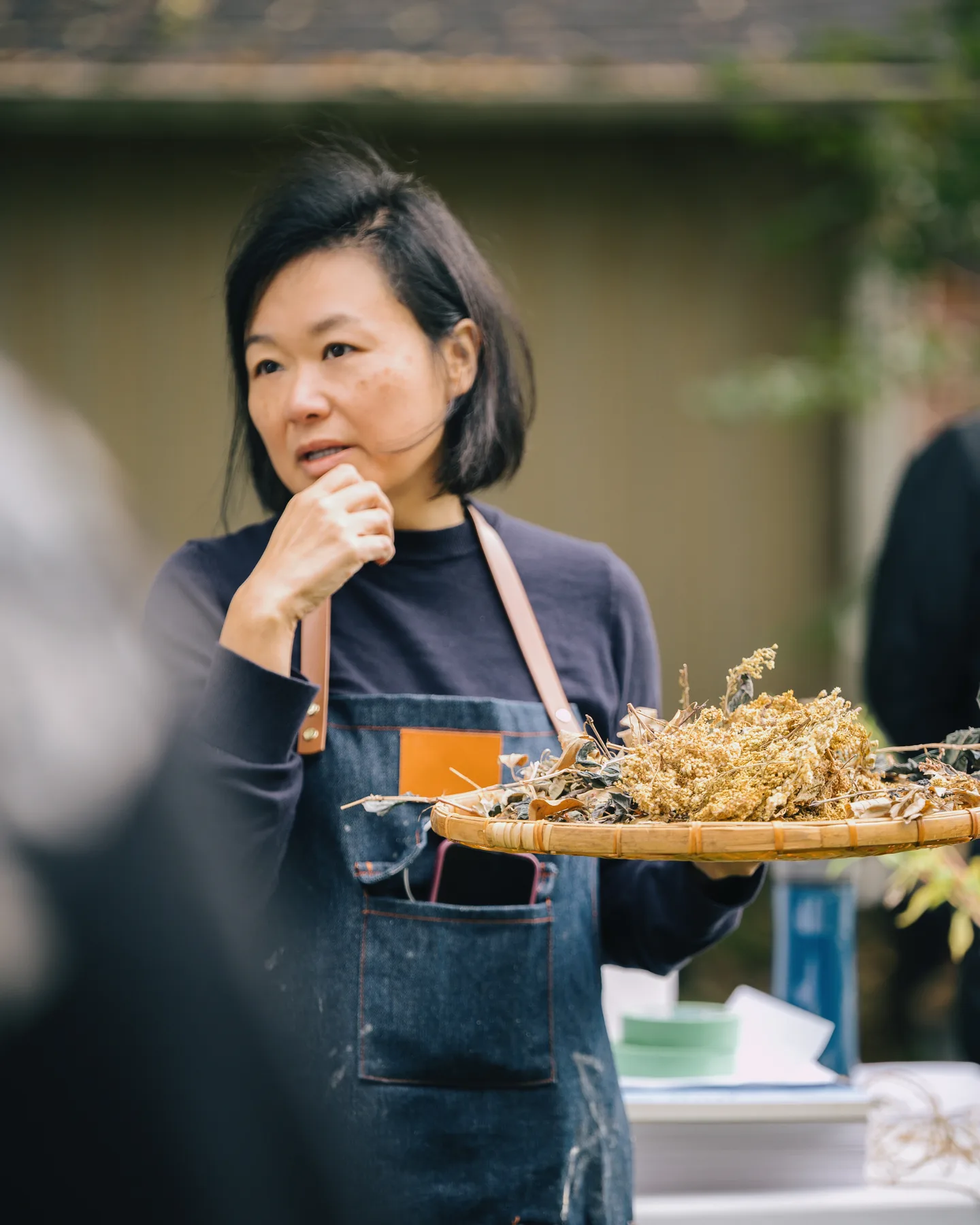 Elaine Chan-Dow holding a tray of botanicals during an outdoor gathering.